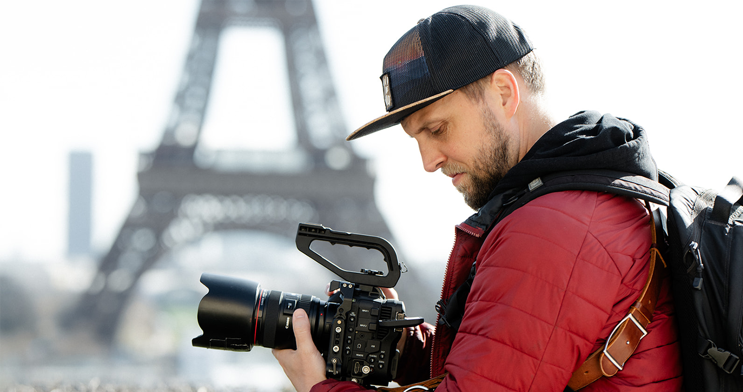 a photographer holds a camera in front of the Eiffel Tower